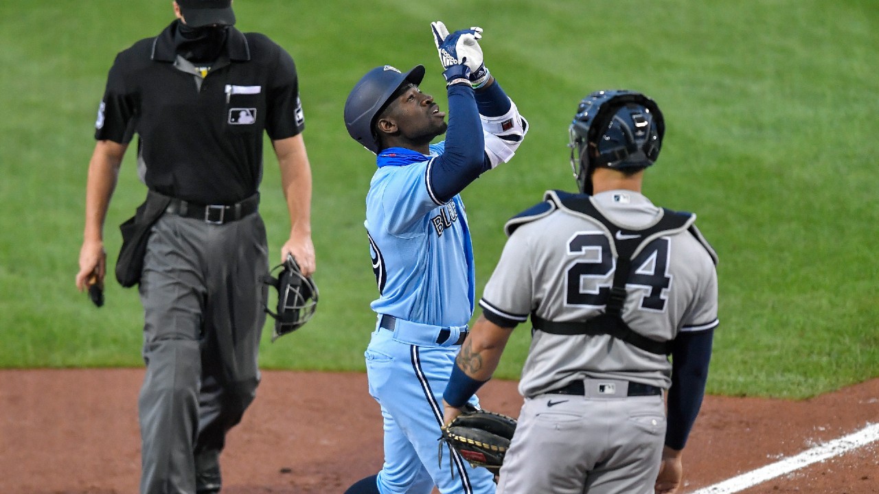 Toronto Blue Jays outfielder Jonathan Davis, centre, points to the sky as he passes New York Yankees catcher Gary Sánchez (24) after hitting a two-run home run. (Adrian Kraus/AP)