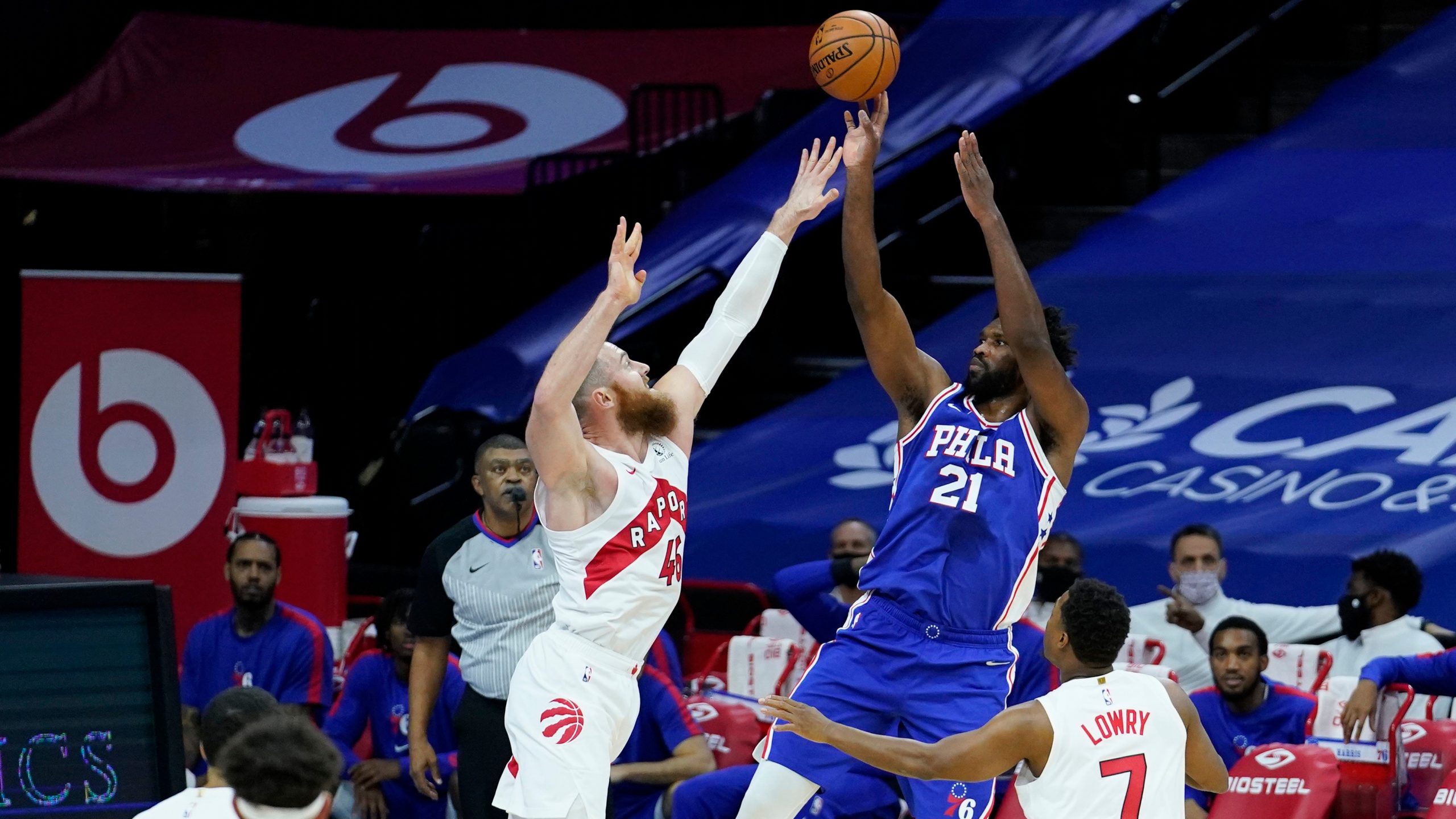 Philadelphia 76ers' Joel Embiid (21) goes up for a shot against Toronto Raptors' Aron Baynes (46) and Kyle Lowry (7) during the first half of an NBA basketball game. (Matt Slocum/AP)