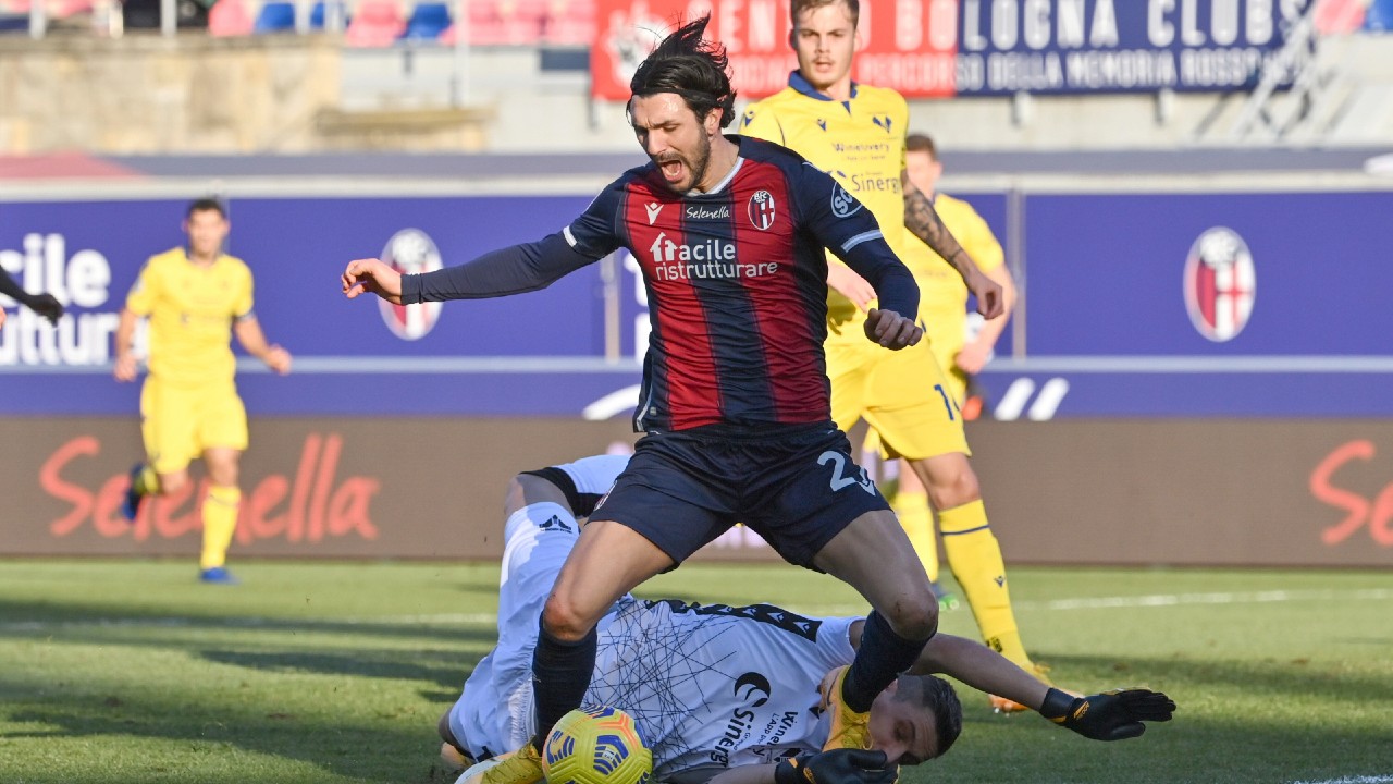 Bologna's Roberto Soriano, standing, and Verona's Marco Silvestri vie for the ball during the Serie A soccer match between Bologna and Verona at the Renato Dall'Ara stadium, in Bologna, Italy, Saturday, Jan. 16, 2021. (Massimo Paolone/LaPresse via AP)