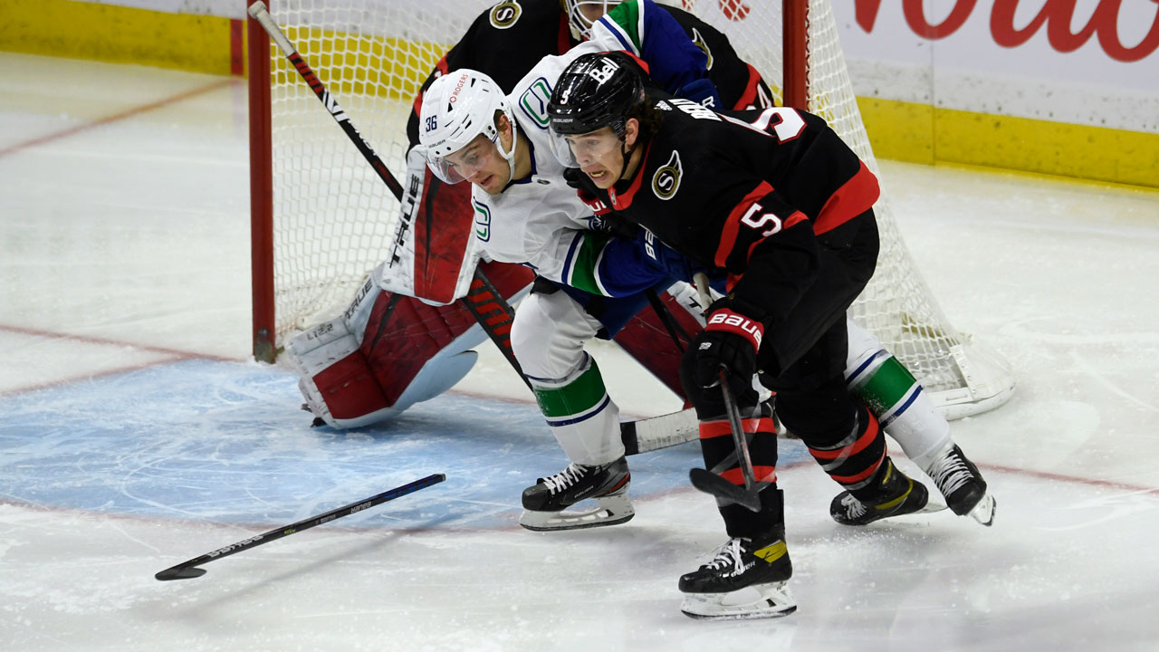 Vancouver Canucks left wing Nils Hoglander (36) loses his stick as he battles with Ottawa defenceman Mike Reilly. (Adrian Wyld/CP)