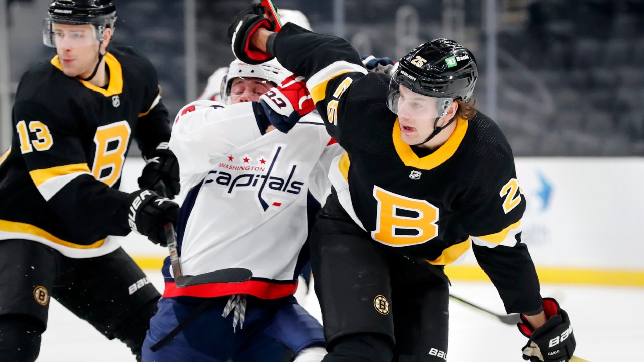 Boston Bruins' Brandon Carlo (25) checks Washington Capitals' Jakub Vrana, center, during the first period of an NHL hockey game Friday, March 5, 2021, in Boston. (Michael Dwyer/AP)