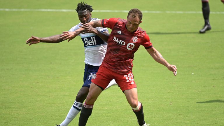 Toronto FC midfielder Nick DeLeon (18) and Vancouver Whitecaps midfielder Janio Bikel (19) compete for the ball during the first half of an MLS soccer match, Saturday, April 24, 2021, in Orlando, Fla. (AP Photo/Phelan M. Ebenhack)