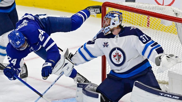 Toronto Maple Leafs' Wayne Simmonds (24) trips over the pad of Winnipeg Jets goaltender Connor Hellebuyck (37) during second period NHL hockey action in Toronto on Thursday, April 15, 2021. (Frank Gunn/CP)