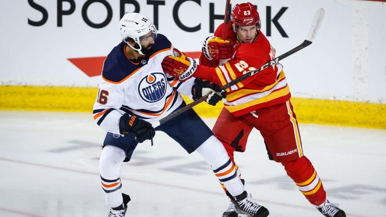 Edmonton Oilers centre Jujhar Khaira, left, checks Calgary Flames centre Sean Monahan. (Jeff McIntosh/CP)