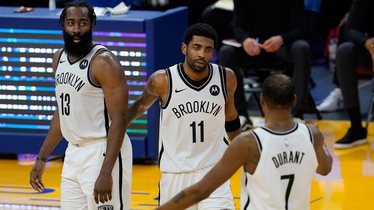 Brooklyn Nets guard Kyrie Irving, middle, gathers with guard James Harden (13) and forward Kevin Durant (7) during the second half against the Golden State Warriors. (Jeff Chiu/AP)