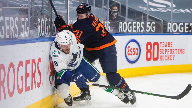 Edmonton Oilers' Slater Koekkoek (20) checks Vancouver Canucks' J.T. Miller (9) during third period NHL action in Edmonton on Saturday, May 15, 2021.(Jason Franson/CP)
