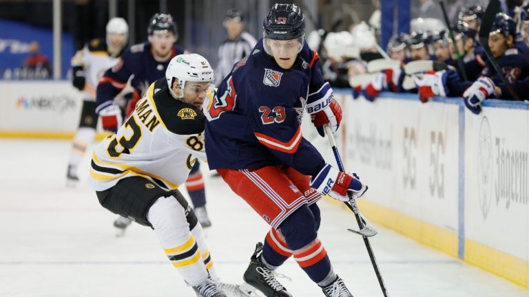 Adam Fox, right, of the New York Rangers, controls the puck as Karson Kuhlman, left, of the Boston Bruins defends during the third period of an NHL game at Madison Square Garden Sunday, Feb. 28, 2021, in New York. (Sarah Stier/Pool Photo via AP)