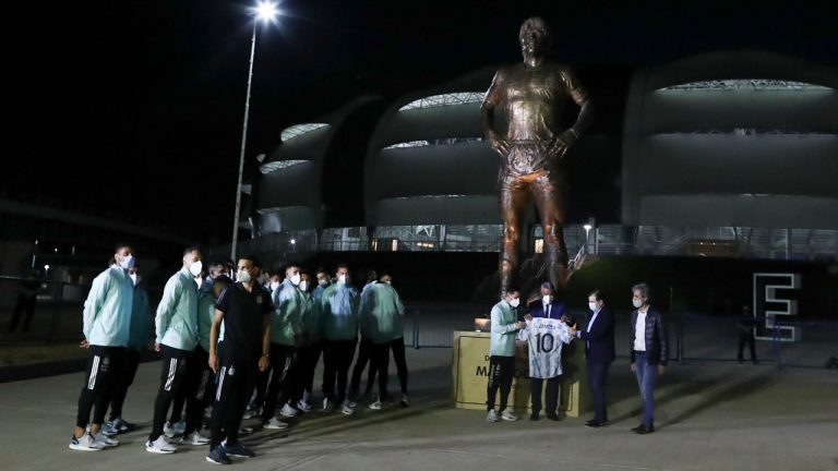 Argentina's Lionel Messi, center left, Argentine Football Association (AFA) President Claudio Tapia, center, and Santiago del Estero province Governor Gerardo Zamora hold a jersey with Maradona's number at the unveiling of a Maradona statue outside Madre de Ciudades stadium prior to a qualifying soccer match for the FIFA World Cup Qatar 2022 between Argentina and Chile. (Agustin Marcarian/AP) 