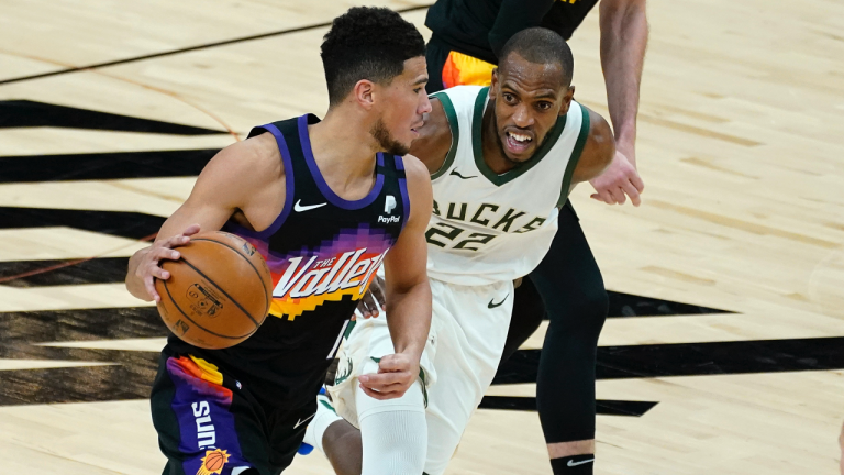 Phoenix Suns guard Devin Booker drives as Milwaukee Bucks forward Khris Middleton (22) defends during the first half of an NBA basketball game Wednesday, Feb. 10, 2021, in Phoenix. (Matt York / AP) 