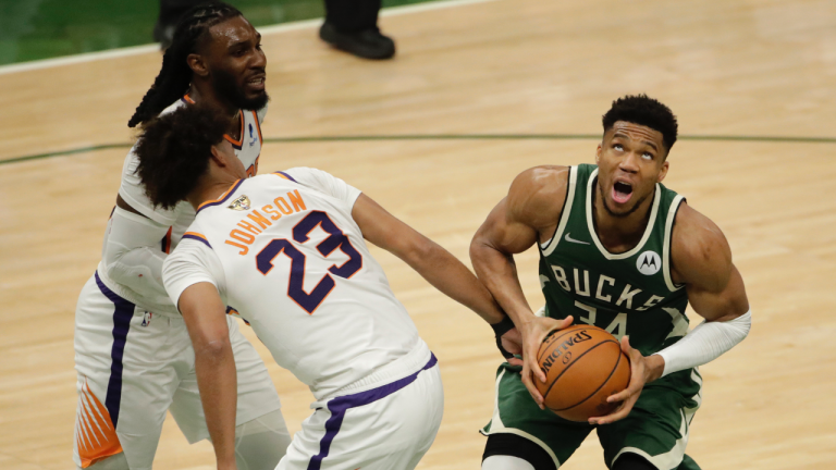 Milwaukee Bucks' Giannis Antetokounmpo (34) looks to shoot past Phoenix Suns' Cameron Johnson (23) and Jae Crowder during the second half of Game 3 of basketball's NBA Finals, Sunday, July 11, 2021, in Milwaukee. (Aaron Gash / AP) 