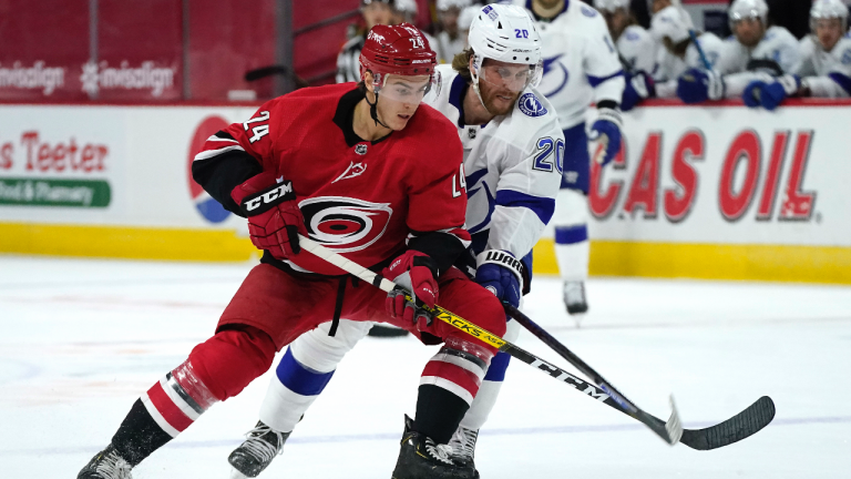 Former Carolina Hurricanes defenceman Jake Bean (24) and Tampa Bay Lightning center Blake Coleman (20) chase the puck during the first period of an NHL hockey game in Raleigh, N.C. (Gerry Broome / AP) 