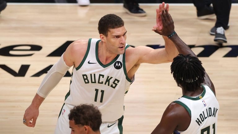 Trae Young #11 of the Atlanta Hawks hangs his head as Brook Lopez #11 and Jrue Holiday #21 of the Milwaukee Bucks celebrate a series win against the Atlanta Hawks in Game 6 of the Eastern Conference Finals. (Kevin C. Cox/Getty Images)