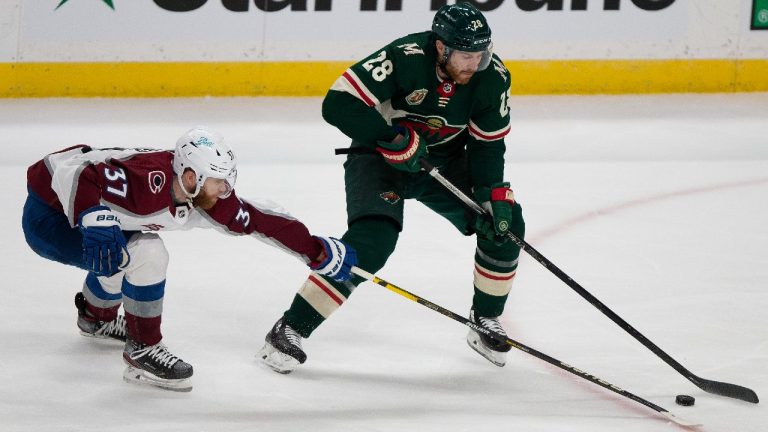 Minnesota Wild's Ian Cole (28) handles the puck against Colorado Avalanche's J.T. Compher (37) in the first period of an NHL hockey game Monday, April 5, 2021, in St. Paul, Minn. (Stacy Bengs/AP) 