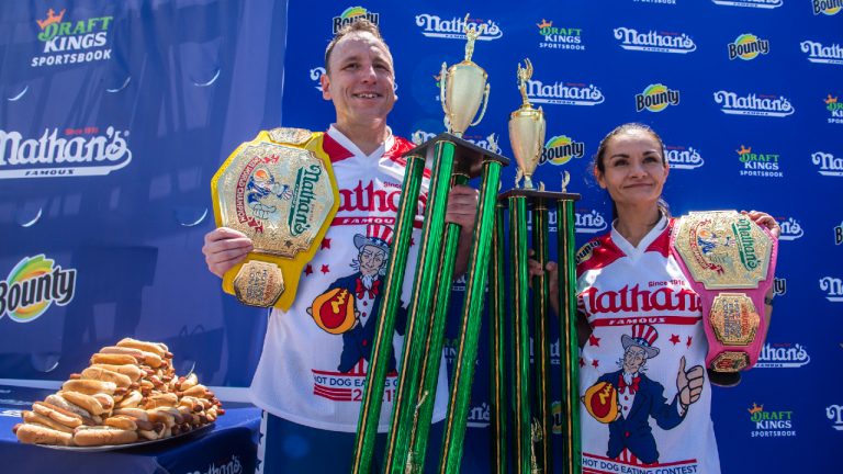 Winners Joey Chestnut and Michelle Lesco pose with their championship belts and trophies at the Nathan's Famous Fourth of July International Hot Dog-Eating Contest in Coney Island's Maimonides Park on Sunday, July 4, 2021, in Brooklyn, New York. (Brittainy Newman/AP) 
