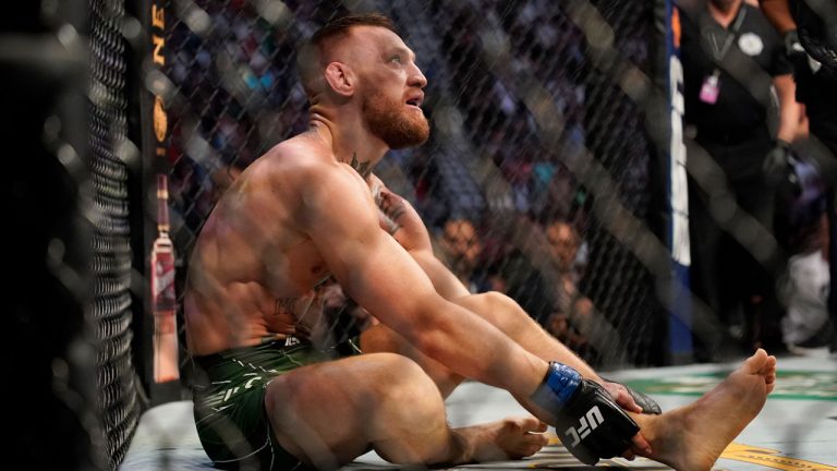 Conor McGregor holds his right ankle while fighting Dustin Poirier during a UFC 264 lightweight mixed martial arts bout. (John Locher/AP) 