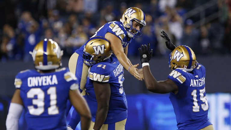 Winnipeg Blue Bombers' kicker Marc Liegghio (13) celebrates with Jermarcus Hardrick (51) and Tobi Antigha (15) after kicking the game winning field goal against the Calgary Stampeders. (John Woods/CP)