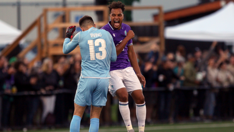 Pacific FCs' Abdoulaye Samake celebrates with goalie Callum Irving after a teammate scores against the Vancouver Whitecaps during first half Canadian Championship Preliminary Round soccer action at Starlight Stadium in Langford, B.C., on Thursday, August 26, 2021. (Chad Hipolito / CP)