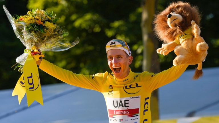 Tour de France winner Tadej Pogacar, wearing the overall leader's yellow jersey, celebrates on the podium after the twenty-first and last stage. (Daniel Cole/AP)