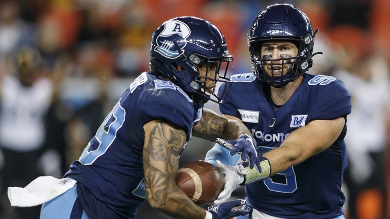 Toronto Argonauts quarterback Nick Arbuckle (9) hands the ball off to running back D.J. Foster (29) in the first half of their CFL football game against the Hamilton Tiger-Cats. (Cole Burston/CP)