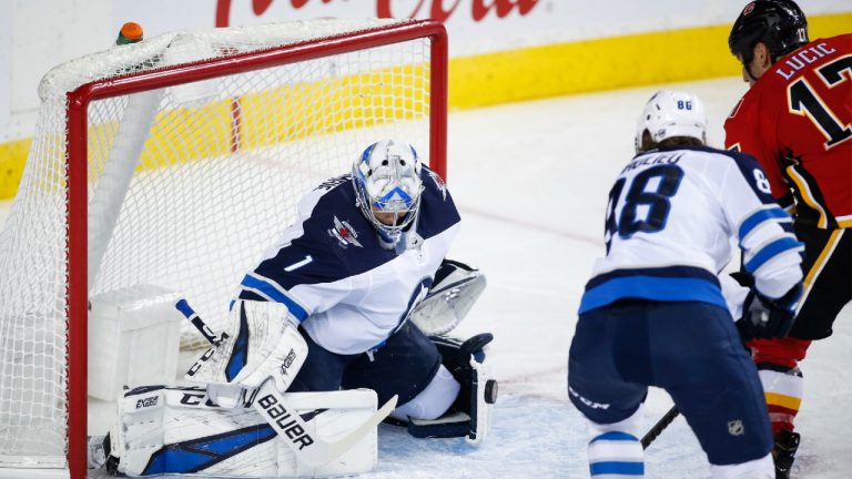 Winnipeg Jets goalie Eric Comrie, left, blocks the net on Calgary Flames' Milan Lucic during first period NHL pre-season hockey action in Calgary, Tuesday, Sept. 24, 2019. (Jeff McIntosh/CP)