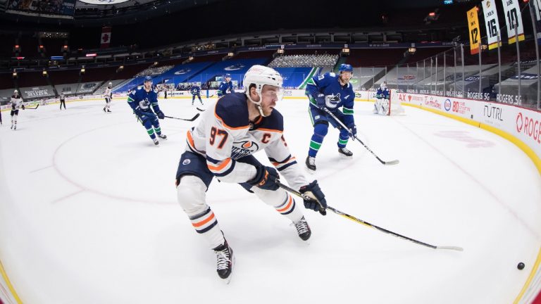 Edmonton Oilers' Connor McDavid (97) skates after the puck while being watched by Vancouver Canucks' Alexander Edler (23), of Sweden, during the first period of an NHL hockey game in Vancouver, B.C., Monday, May 3, 2021. (Darryl Dyck/CP)