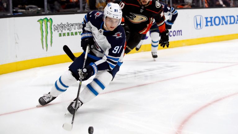 Winnipeg Jets center Cole Perfetti, left, controls the puck in front of Anaheim Ducks center Benoit-Olivier Groulx during the second period of an NHL hockey game in Anaheim, Calif., Wednesday, Oct. 13, 2021. (Alex Gallardo/AP)