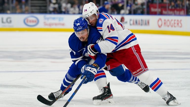 Toronto Maple Leafs forward Auston Matthews (34) is held by New York Rangers forward Greg McKegg (14) during second period NHL action in Toronto, Monday, Oct. 18, 2021. (Evan Buhler/The Canadian Press) 
