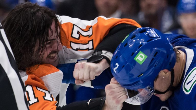 Philadelphia Flyers' Zack MacEwen, left, grabs Vancouver Canucks' Luke Schenn's visor as they fight during the second period of an NHL hockey game in Vancouver, on Thursday, October 28, 2021. (Darryl Dyck/The Canadian Press)
