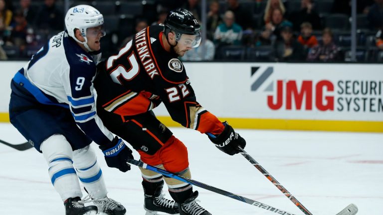 Winnipeg Jets center Andrew Copp, left, defends against a shot by Anaheim Ducks defenseman Kevin Shattenkirk, right, during the second period of an NHL hockey game in Anaheim, Calif., Tuesday, Oct. 26, 2021. (Alex Gallardo/AP Photo) 
