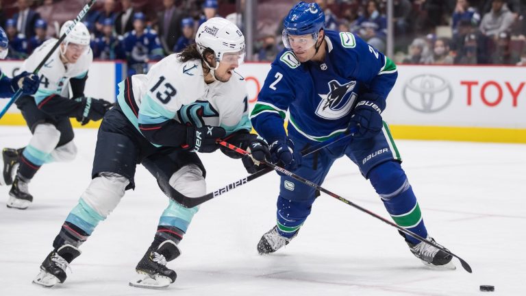 Vancouver Canucks' Luke Schenn (2) checks Seattle Kraken's Brandon Tanev (13) during the first period of a pre-season NHL hockey game in Vancouver, on Tuesday, October 5, 2021. (Darryl Dyck/THE CANADIAN PRESS)
