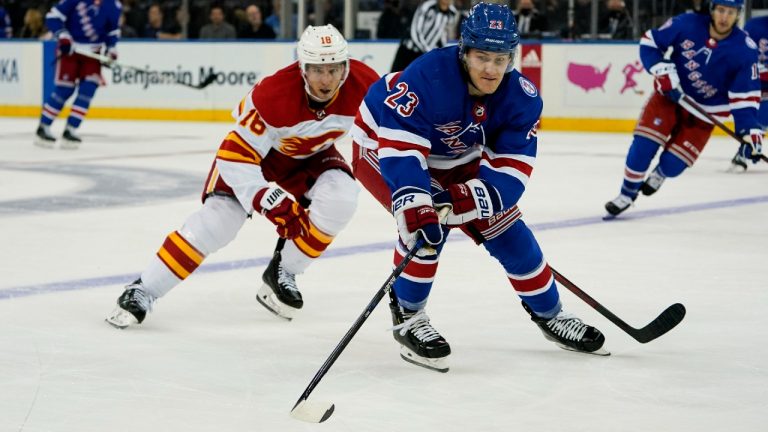 New York Rangers defenseman Adam Fox (23) and Calgary Flames defenseman Nikita Zadorov (16) chase the puck during the first period of an NHL hockey game, Monday, Oct. 25, 2021, in New York (John Minchillo/AP).
