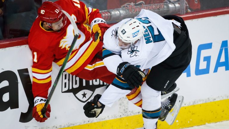 San Jose Sharks' Nicolas Meloche, right, checks Calgary Flames' Mikael Backlund during first period NHL hockey action in Calgary, Tuesday, Nov. 9, 2021 (Jeff McIntosh/CP).