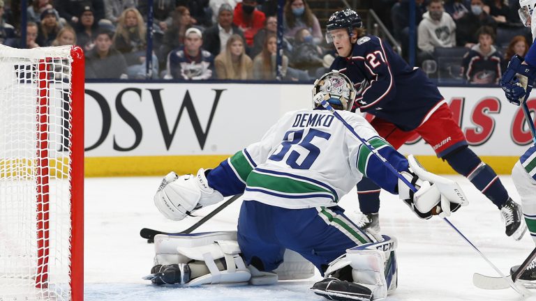 Columbus Blue Jackets' Adam Boqvist, top, prepares to shoot against Vancouver Canucks' Thatcher Demko during the second period of an NHL hockey game. (Jay LaPrete/AP)