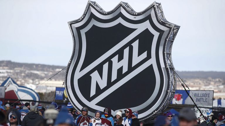 Fans pose below the NHL logo outside Falcon Stadium before an NHL Stadium Series outdoor hockey game between the Los Angeles Kings and Colorado Avalanche, at Air Force Academy, Colo. on Sat., Feb.15, 2020. Canada’s smallest province is looking to boost its tourism profile through a deal with the National Hockey League. (David Zalubowski/AP)