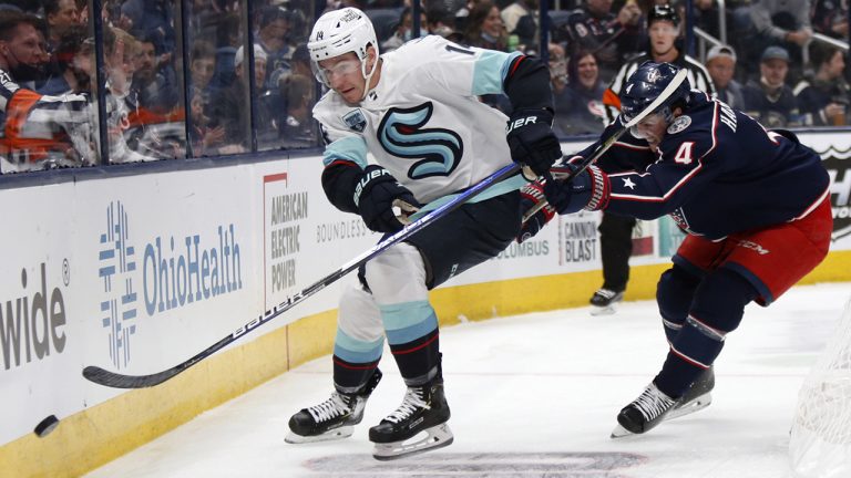 Seattle Kraken forward Nathan Bastian, left, passes the puck in front of Columbus Blue Jackets defenceman Scott Harrington. (Paul Vernon/AP Photo)