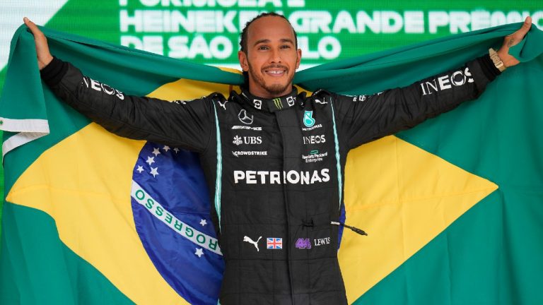 Mercedes' Lewis Hamilton holds a Brazilian flag as he celebrates wining the Brazilian Formula One Grand Prix at the Interlagos race track in Sao Paulo, Brazil, Sunday, Nov. 14, 2021. (Andre Penner/AP)