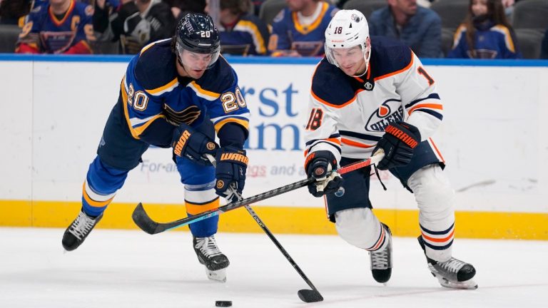 St. Louis Blues' Brandon Saad (20) and Edmonton Oilers' Zach Hyman (18) battle for a loose puck during the third period of an NHL hockey game Sunday, Nov. 14, 2021, in St. Louis. (Jeff Roberson/AP) 
