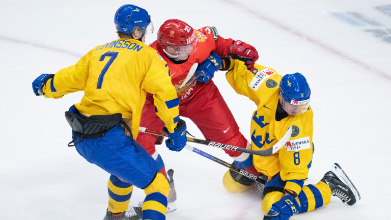 Sweden's Leo Lööf and Simon Edvinsson fight for control of the puck with Russia's Nikita Guslistov during second period IIHF World Junior Hockey Championship action in Red Deer, Alberta on Sunday, December 26, 2021.  CP/file)