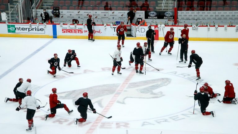 Arizona Coyotes players and coaches pause on the ice during NHL hockey practice at Gila River Arena, Monday, July 13, 2020, in Glendale, Ariz. (Ross D. Franklin/AP Photo) 