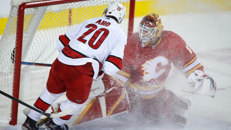 Carolina Hurricanes' Sebastian Aho, left, scores the game-winning goal on Calgary Flames goalie Jacob Markstrom during overtime NHL hockey action against the Calgary Flames in Calgary, Thursday, Dec. 9, 2021 (Jeff McIntosh/CP).
