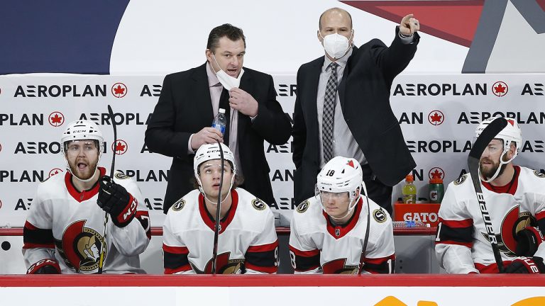 Ottawa Senators head coach D.J. Smith, left, and assistant coach Davis Payne talk to their players during third period NHL action. (John Woods/CP)