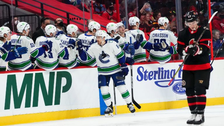 Vancouver Canucks centre Tyler Motte (64) celebrates a goal with teammates on the bench as Ottawa Senators centre Adam Gaudette (17) makes his way up ice during second period NHL action in Ottawa on Wednesday, Dec. 1, 2021. (Sean Kilpatrick/CP).