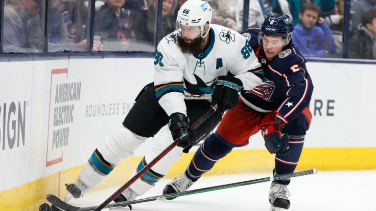 San Jose Sharks' Brent Burns, left, carries the puck behind the net as Columbus Blue Jackets' Andrew Peeke defends during the third period of an NHL hockey game Sunday, Dec. 5, 2021, in Columbus, Ohio. (Jay LaPrete/AP)