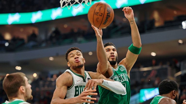 Boston Celtics forward Jayson Tatum, center, reaches for a rebound against Milwaukee Bucks forward Giannis Antetokounmpo (34) after chipping the tooth of guard Jaylen Brown, right, during the first half of an NBA basketball game. (Jon Durr/AP) 