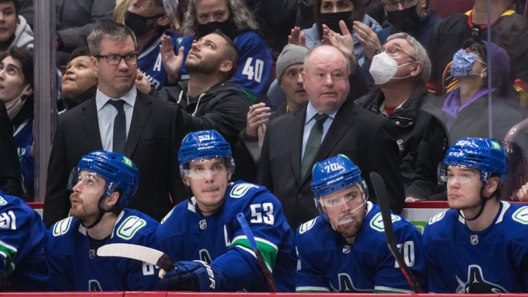 New Vancouver Canucks head coach Bruce Boudreau, back right, and assistant coach Scott Walker, back left, stand on the bench during first-period NHL hockey action against the Los Angeles Kings, in Vancouver, B.C., Monday, Dec. 6, 2021. (Darryl Dyck/THE CANADIAN PRESS) 
