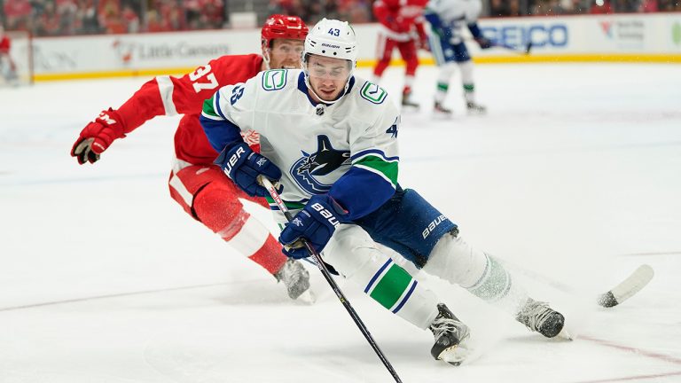 Vancouver Canucks defenceman Quinn Hughes (43) protects the puck from Detroit Red Wings right wing Carter Rowney (37) in the third period of an NHL hockey game Saturday, Oct. 16, 2021, in Detroit. (Paul Sancya/AP)