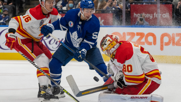 Calgary Flames' Dan Vladar makes a save as Nikita Zadorov tries to control Toronto Maple Leafs' Michael Bunting on Friday November 12, 2021. (CP/file)