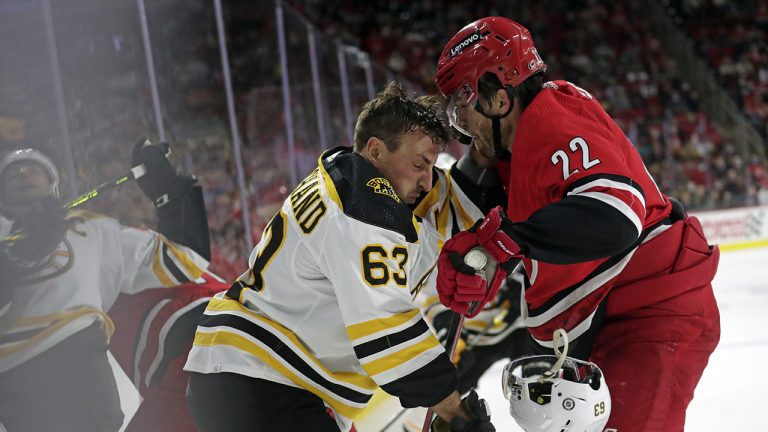 Boston Bruins center Brad Marchand (63) loses his helmet as he battles along the boards with Carolina Hurricanes defenceman Brett Pesce (22). (Chris Seward/AP)