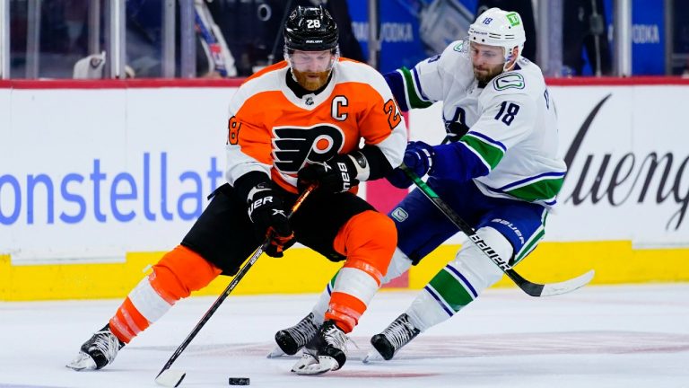 Philadelphia Flyers' Claude Giroux, left, and Vancouver Canucks' Jason Dickinson battle for the puck during the third period of an NHL hockey game, Friday, Oct. 15, 2021, in Philadelphia. (Matt Slocum/AP)