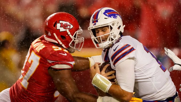 Buffalo Bills quarterback Josh Allen, right, is slowed by Kansas City Chiefs defensive end Alex Okafor (97) during the second half of an NFL football game Sunday, Oct. 10, 2021, in Kansas City, Mo. (Charlie Riedel/AP Photo) 
